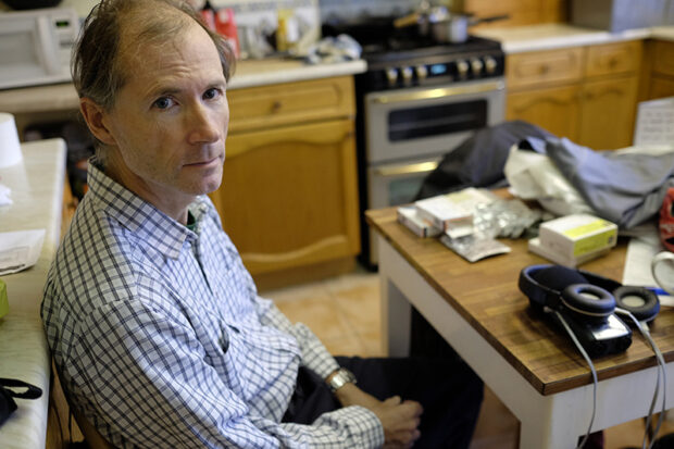 My father in her kitchen exuding discomfort; unable to be her true self in the moment I hold my camera. From 'Mother, Father' by Lucie Rachel. ©Lucie Rachel 2015, all rights reserved.