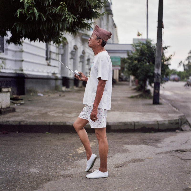 A man takes his early morning walk at 5am, with his radio through the streets of downtown Yangon, Myanmar. @ Sophie Gerrard, all rights reserved.